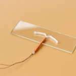 Das Bild zeigt eine T-förmige Spirale mit Kupfer (Intrauterine Verhütungsvorrichtung) auf einem Objektträger.