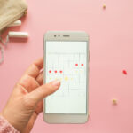 Gezeigt wird ein digitaler Kalender der die Monatsblutung skizziert. Auch erkennbar sind Utensilien wie Tampons und Tabletten.